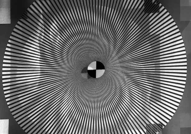 An optical illusion of a black and white striped, circular funnel that leads to a black and white checkered board.