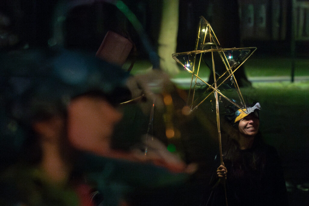 A person holding a pentacle made out of bamboo at night.