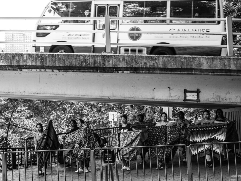 A group of dancers practices under a bridge. (Xyza Bacani, Dancers, 2017).